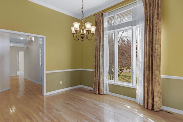 unfurnished room featuring light hardwood / wood-style floors, crown molding, a wealth of natural light, and a chandelier