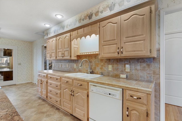 kitchen with backsplash, white dishwasher, sink, light brown cabinets, and tile countertops