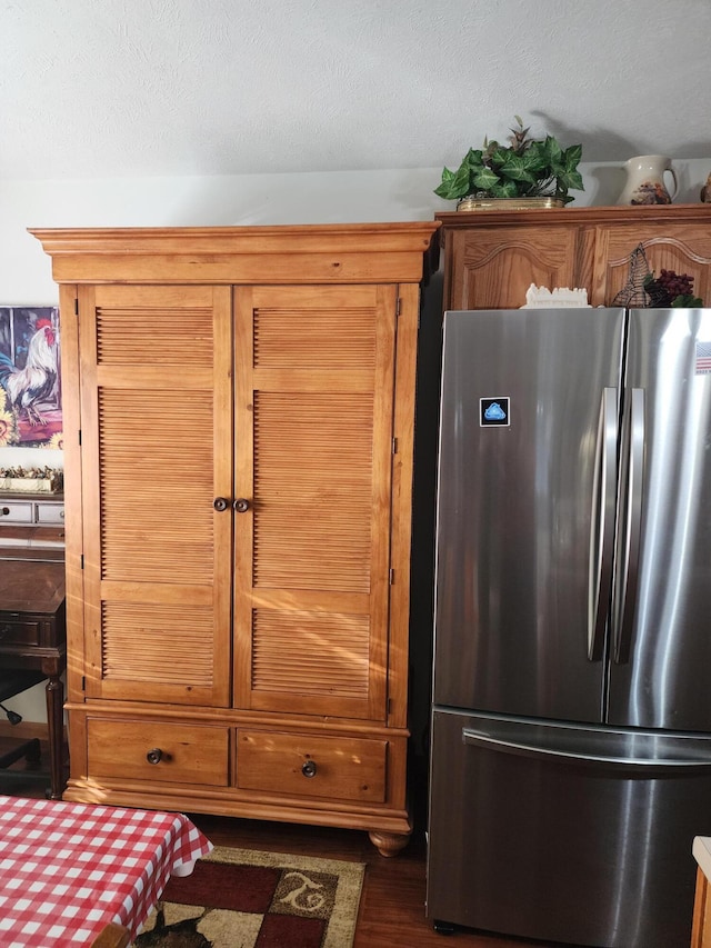 interior space with stainless steel fridge, a textured ceiling, and dark wood-type flooring