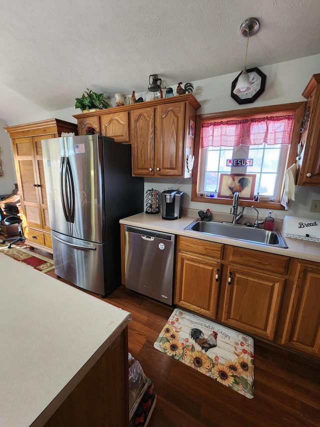 kitchen with a textured ceiling, dark hardwood / wood-style flooring, sink, and stainless steel appliances