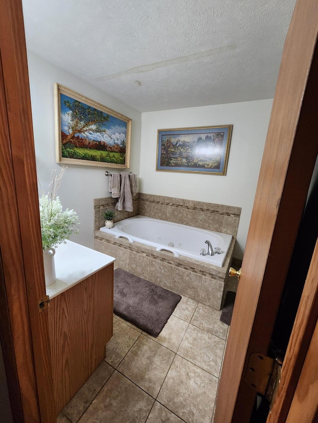 bathroom featuring tile patterned floors, vanity, a relaxing tiled tub, and a textured ceiling