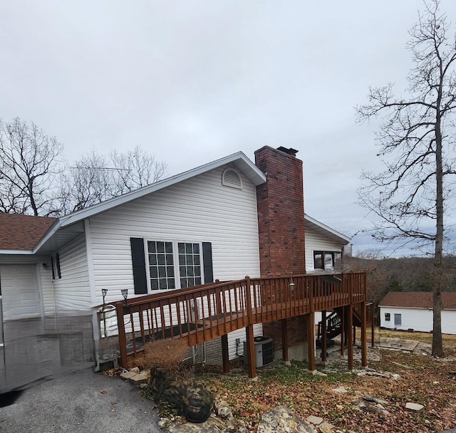 view of home's exterior with a deck, stairs, a chimney, and central AC