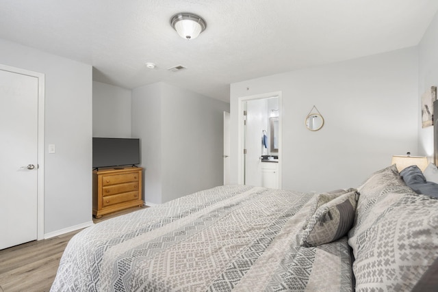 bedroom featuring ensuite bathroom and light hardwood / wood-style floors