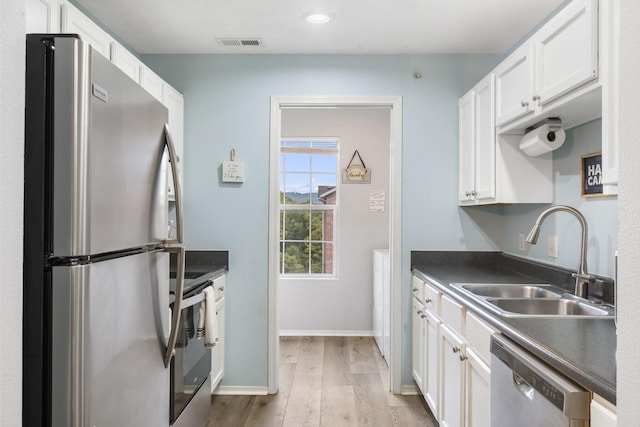 kitchen with hardwood / wood-style floors, sink, white cabinets, and stainless steel appliances