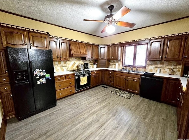 kitchen with decorative backsplash, a textured ceiling, sink, black appliances, and light hardwood / wood-style floors