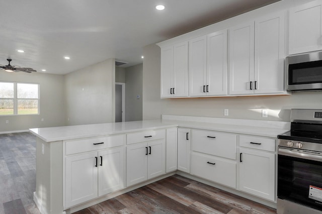 kitchen with dark wood-type flooring, white cabinets, ceiling fan, kitchen peninsula, and stainless steel appliances