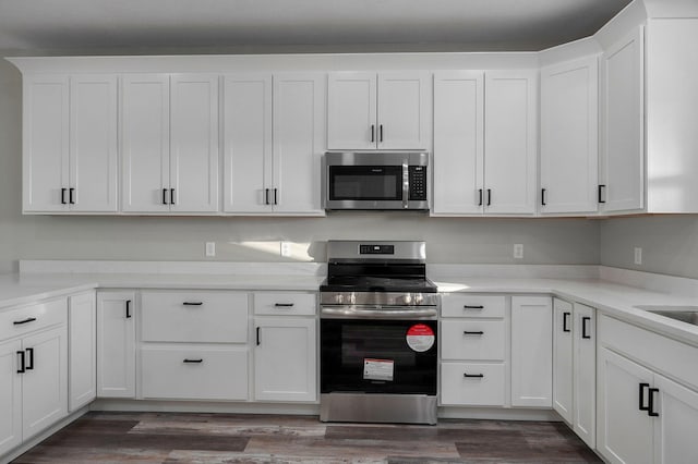 kitchen with white cabinets, dark hardwood / wood-style flooring, and stainless steel appliances