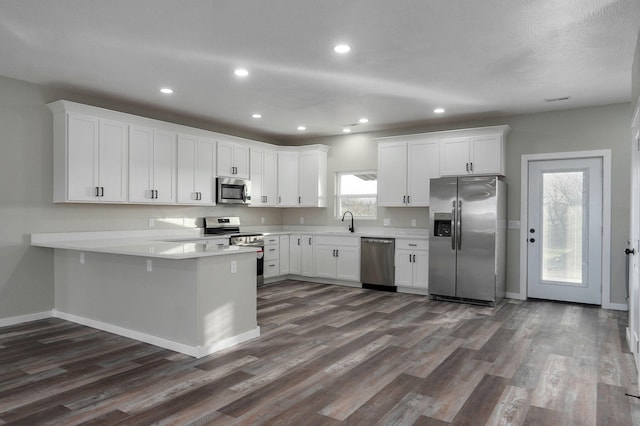 kitchen featuring kitchen peninsula, appliances with stainless steel finishes, white cabinetry, and sink