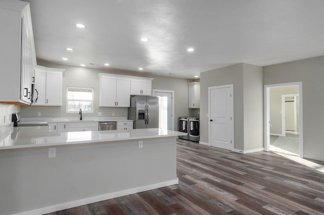 kitchen featuring sink, kitchen peninsula, washer and dryer, white cabinetry, and stainless steel appliances