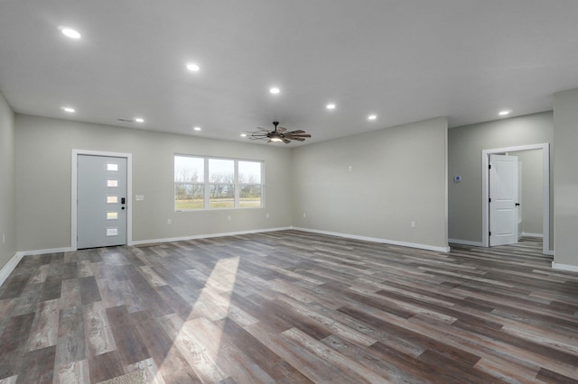 unfurnished living room featuring ceiling fan and dark wood-type flooring