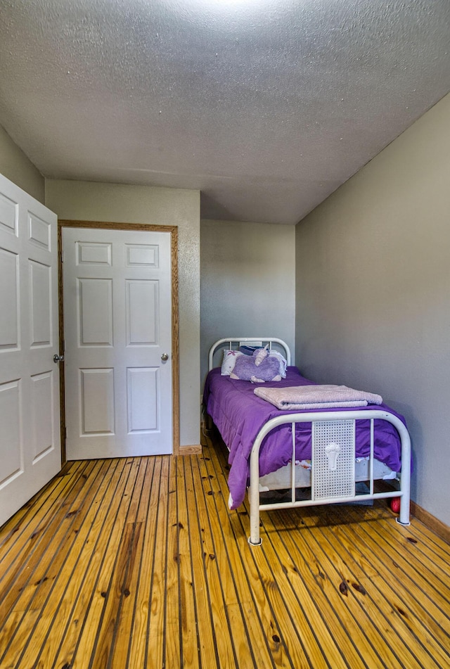 bedroom with wood-type flooring and a textured ceiling