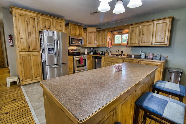 kitchen featuring a center island, an inviting chandelier, sink, appliances with stainless steel finishes, and a breakfast bar area