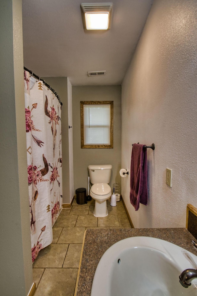 bathroom with tile patterned flooring, toilet, walk in shower, and sink