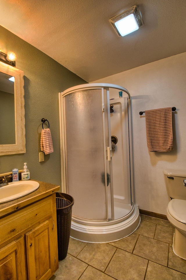 bathroom with a textured ceiling, vanity, toilet, and a shower with shower door