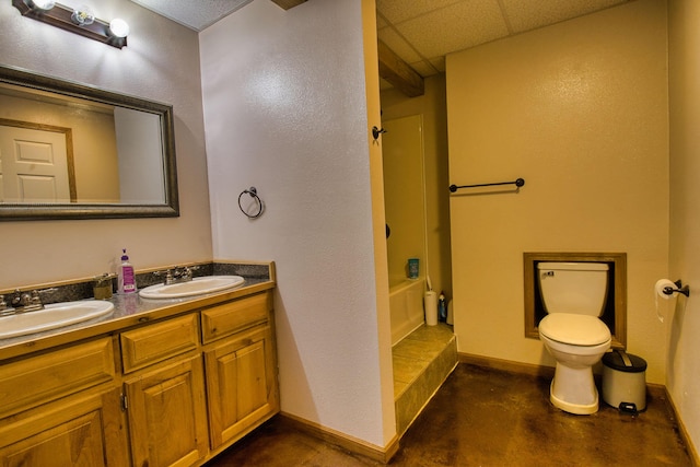 full bathroom with shower / bath combination, a drop ceiling, vanity, concrete floors, and toilet