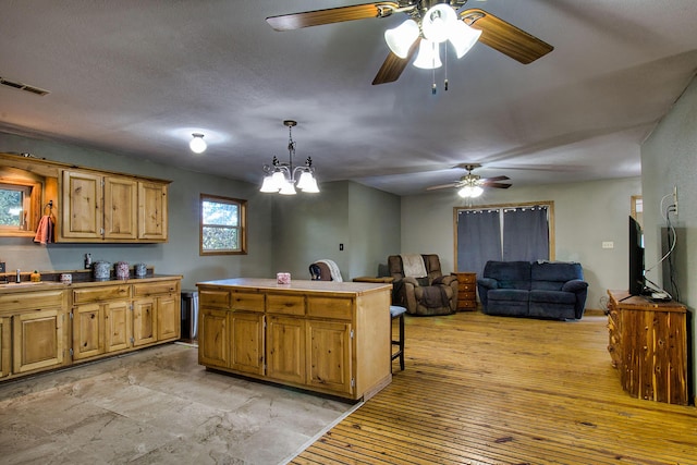 kitchen featuring sink, a center island, a kitchen breakfast bar, a notable chandelier, and decorative light fixtures