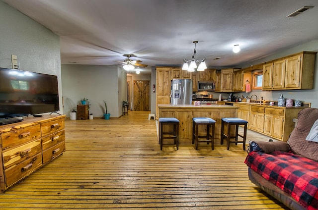 kitchen featuring a breakfast bar, sink, appliances with stainless steel finishes, a notable chandelier, and light hardwood / wood-style floors