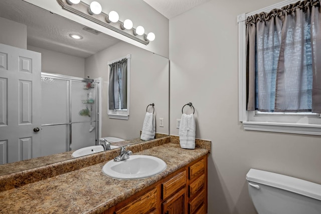 bathroom featuring a textured ceiling, vanity, toilet, and walk in shower