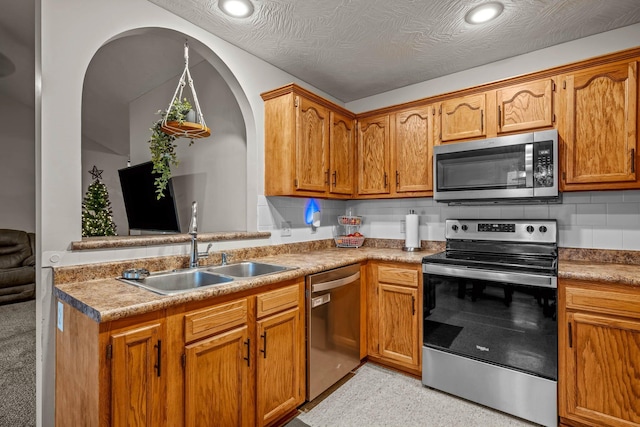 kitchen with a textured ceiling, decorative backsplash, sink, and stainless steel appliances