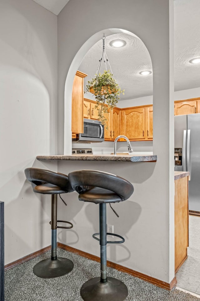 kitchen with light brown cabinets, sink, a textured ceiling, and appliances with stainless steel finishes