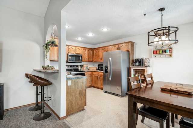 776 S Pinehurst St, Nixa, MO 65714 - kitchen featuring appliances with stainless steel finishes, a peninsula, hanging light fixtures, light countertops, and brown cabinets