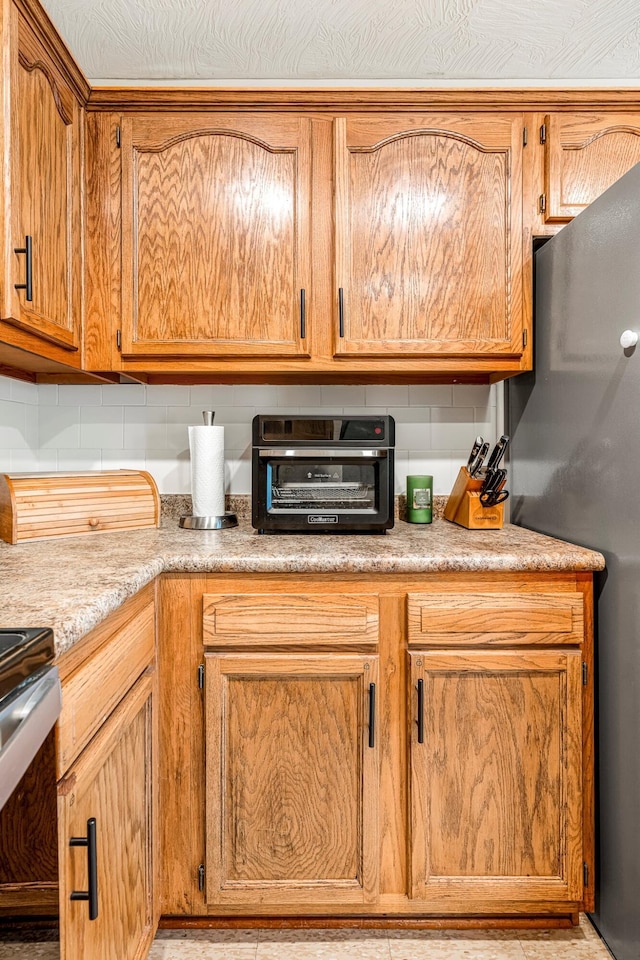776 S Pinehurst St, Nixa, MO 65714 - kitchen featuring stainless steel appliances, tasteful backsplash, light countertops, and brown cabinetry