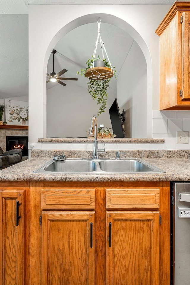 776 S Pinehurst St, Nixa, MO 65714 - kitchen featuring a sink, ceiling fan, stainless steel dishwasher, light countertops, and a glass covered fireplace