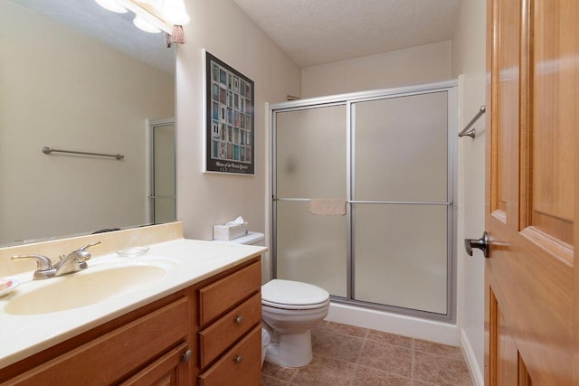 bathroom featuring toilet, a textured ceiling, vanity, a shower with door, and tile patterned flooring