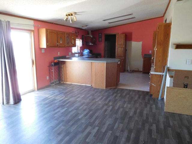 kitchen with brown cabinets, a peninsula, ornamental molding, and wood finished floors