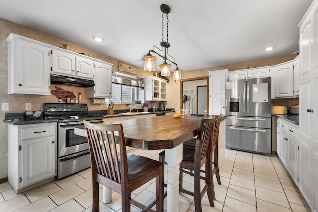 kitchen with light tile patterned flooring, hanging light fixtures, white cabinets, and stainless steel appliances