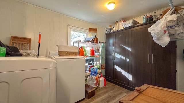 clothes washing area with cabinets, washing machine and dryer, and light hardwood / wood-style floors