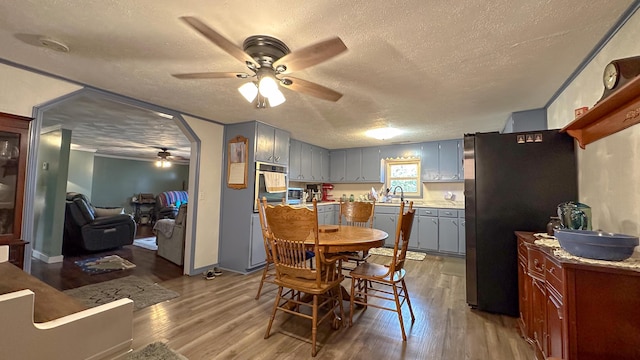 dining space featuring wood-type flooring, a textured ceiling, ceiling fan, and sink