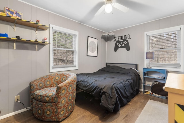 bedroom featuring wood-type flooring, crown molding, ceiling fan, and wooden walls