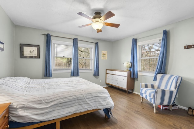 bedroom featuring multiple windows, ceiling fan, wood-type flooring, and a textured ceiling