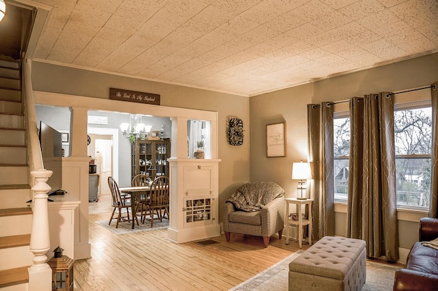 living room featuring light wood-type flooring, crown molding, and a notable chandelier