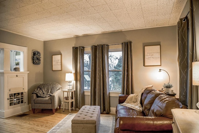 sitting room with crown molding and light hardwood / wood-style flooring