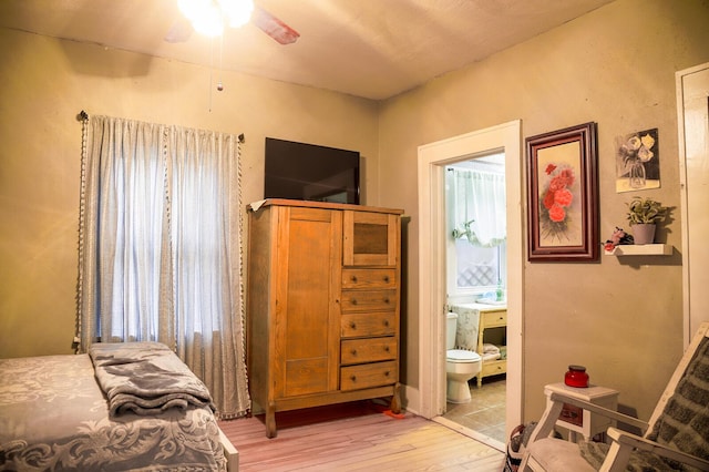 bedroom featuring ceiling fan, light wood-type flooring, connected bathroom, and multiple windows