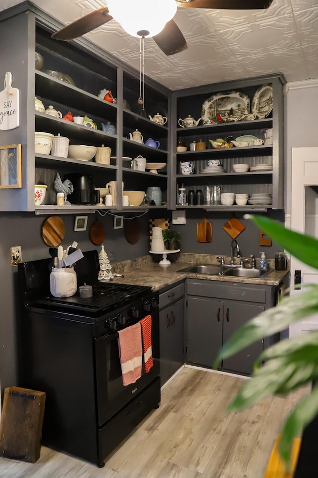 bar featuring ceiling fan, sink, black range, and light hardwood / wood-style flooring