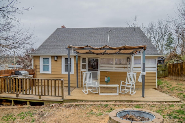 rear view of house with a wooden deck and an outdoor fire pit