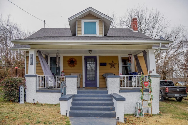 bungalow-style home featuring covered porch and a front yard