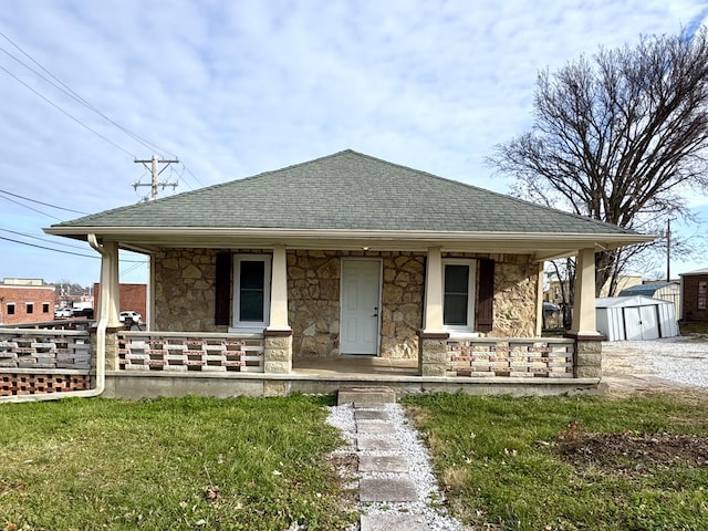 bungalow-style home with covered porch, a shed, and a front yard