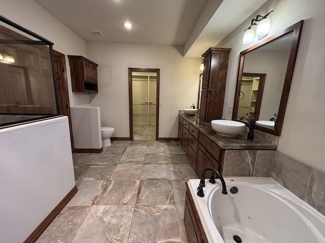 bathroom with tiled tub, vanity, and toilet