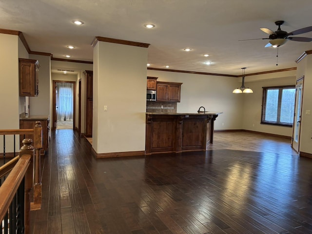 kitchen featuring decorative backsplash, dark hardwood / wood-style flooring, crown molding, decorative light fixtures, and a breakfast bar area