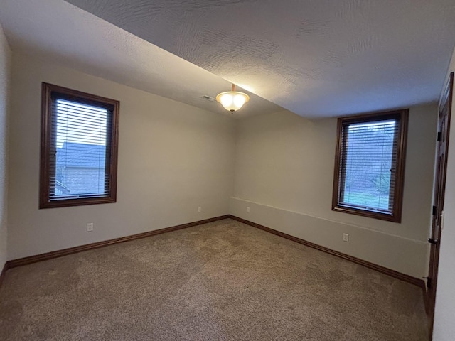 carpeted empty room with a textured ceiling