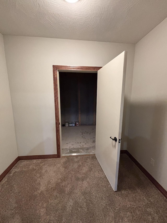 spare room featuring dark colored carpet and a textured ceiling