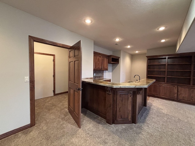 kitchen with a kitchen bar, kitchen peninsula, sink, and carpet floors