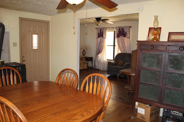 dining space with a textured ceiling, ceiling fan, and dark wood-type flooring