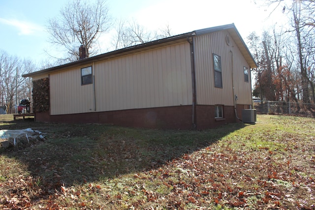 view of side of property featuring cooling unit and a yard