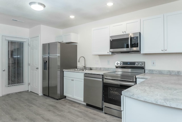 kitchen featuring white cabinetry, sink, stainless steel appliances, and light hardwood / wood-style floors