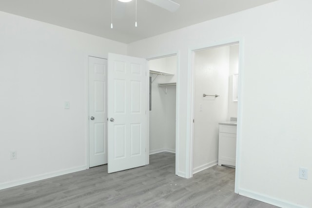 unfurnished bedroom with ceiling fan, ensuite bath, a walk in closet, and light hardwood / wood-style flooring